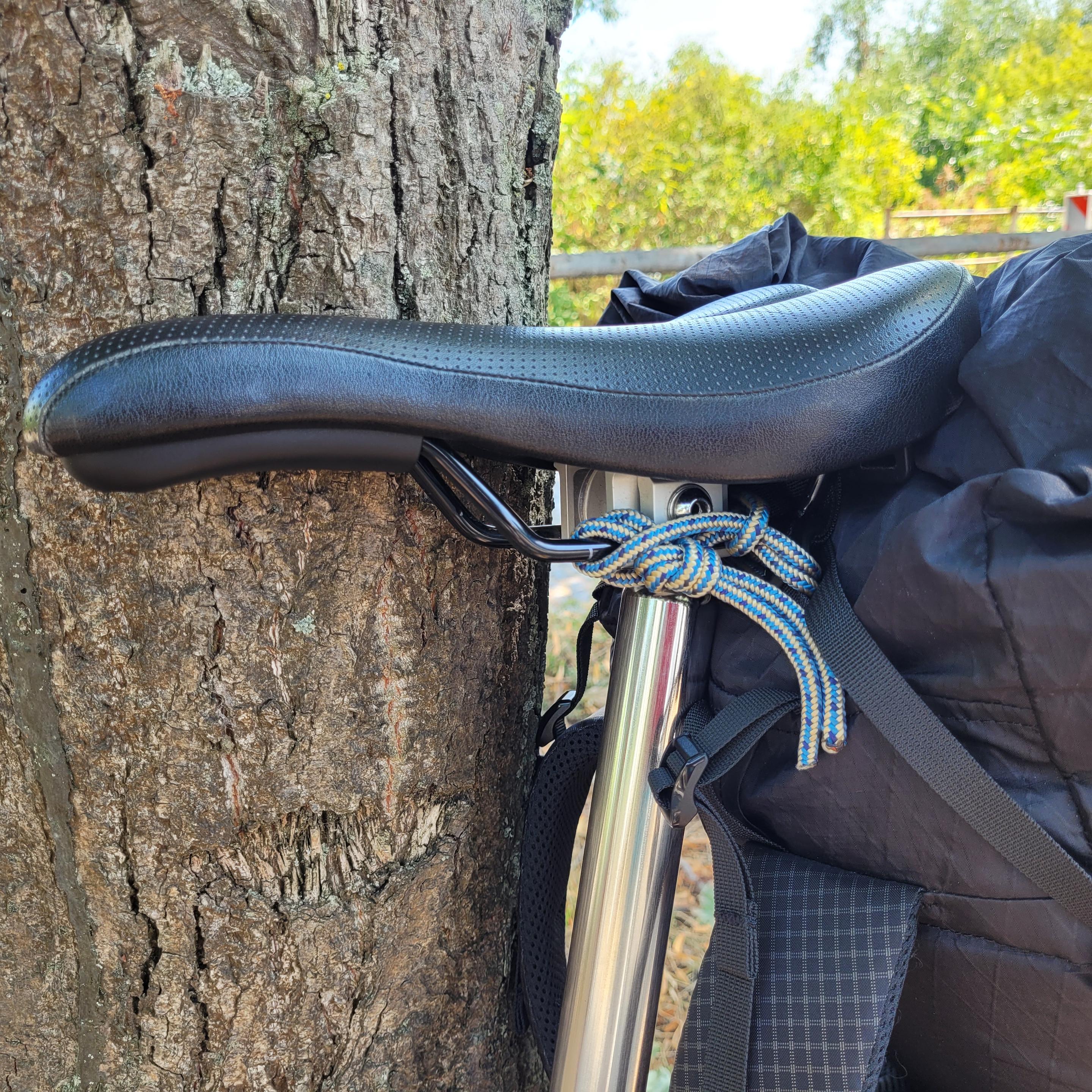 Detailaufnahme vom Sattel, an den der obere Teil des Rucksacks mit einem Stück Reepschnur befestigt ist.