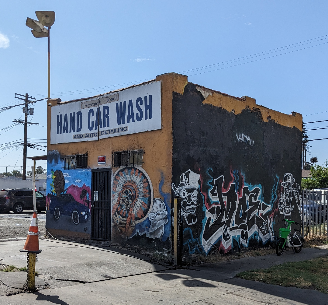 Car wash building with multiple styles of mural/graffiti on it