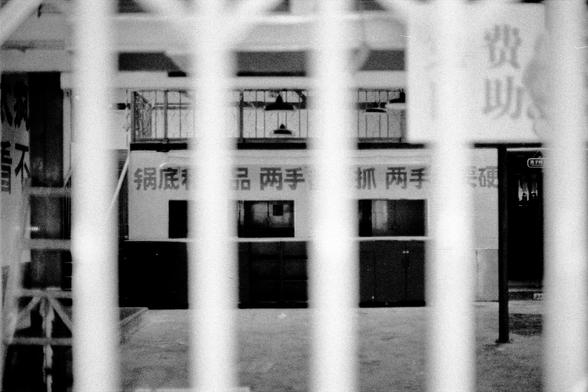 Lucky LUCKY SHD 400 (FF)

English
A black-and-white photograph taken through vertical metal bars, showing a building with large windows and Chinese characters on its facade. The bars are in sharp focus in the foreground, while the building is slightly blurred in the background.
中文
一张通过垂直金属栏杆拍摄的黑白照片，照片中有一栋带有大窗户的建筑，其立面上有中文字样。前景中金属栏杆清晰对焦，而背景中的建筑略显模糊。
