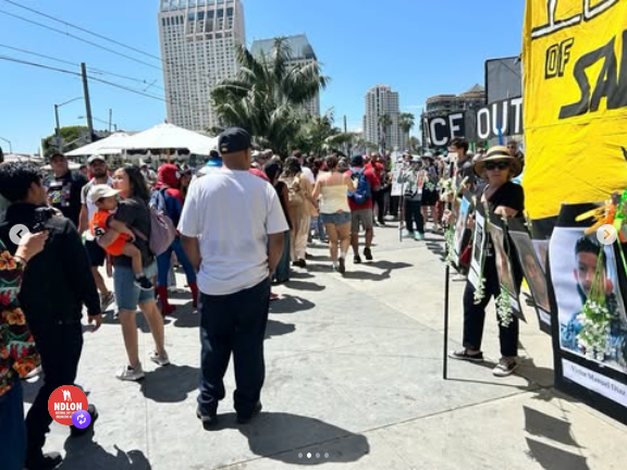 Scene from a march in San Diego yesterday. The street is full of people. There's a yellow banner off to the left that reads "ICE OUT OF SAN DIEGO." A large, diverse crowd is marching along with people of all ages. There's a protestor in a Spider Man costume, which I guess is like black bloc with a sense of humor.