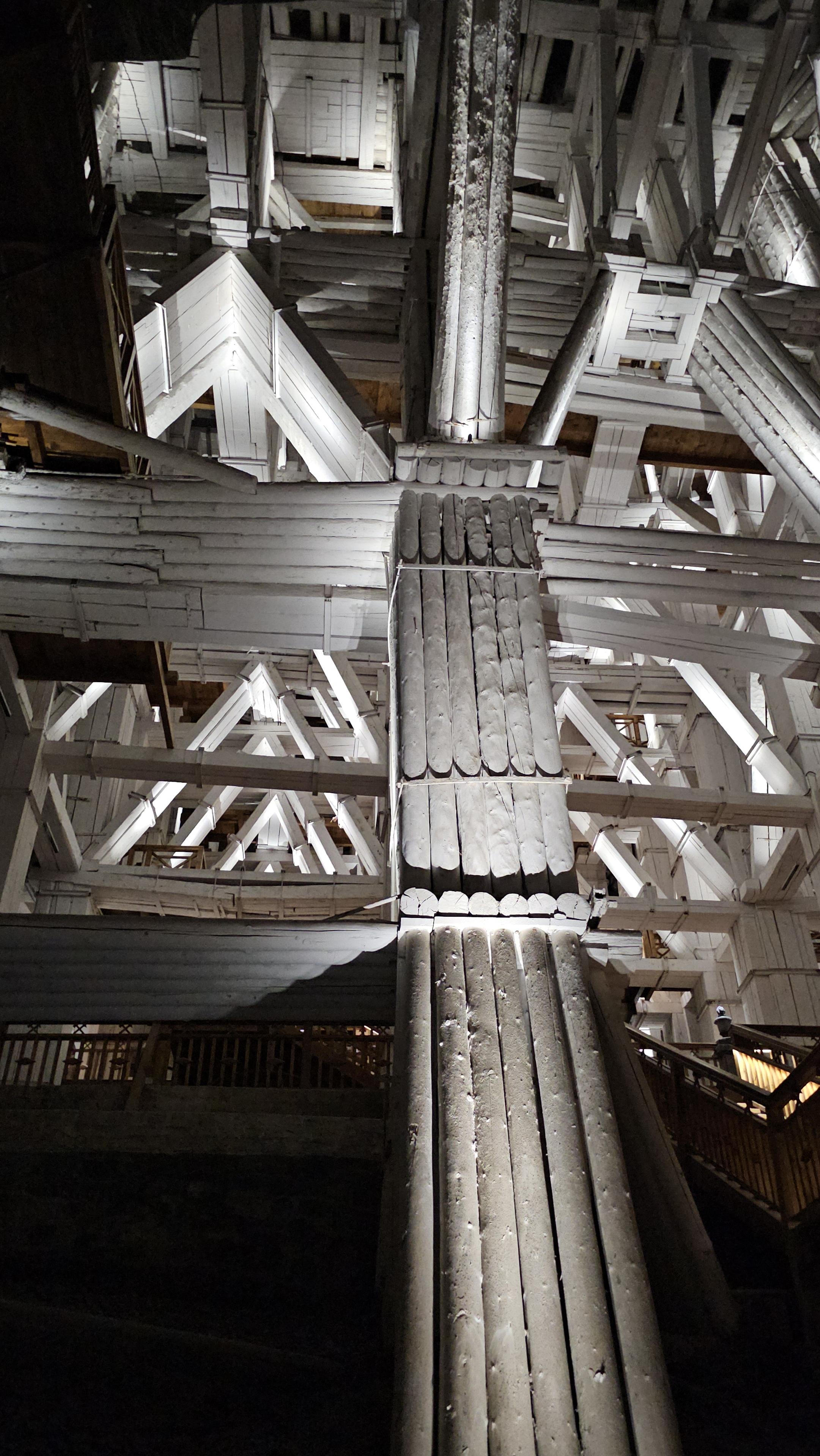 A complex, underground, support framework made from whole tree trunks, painted white.