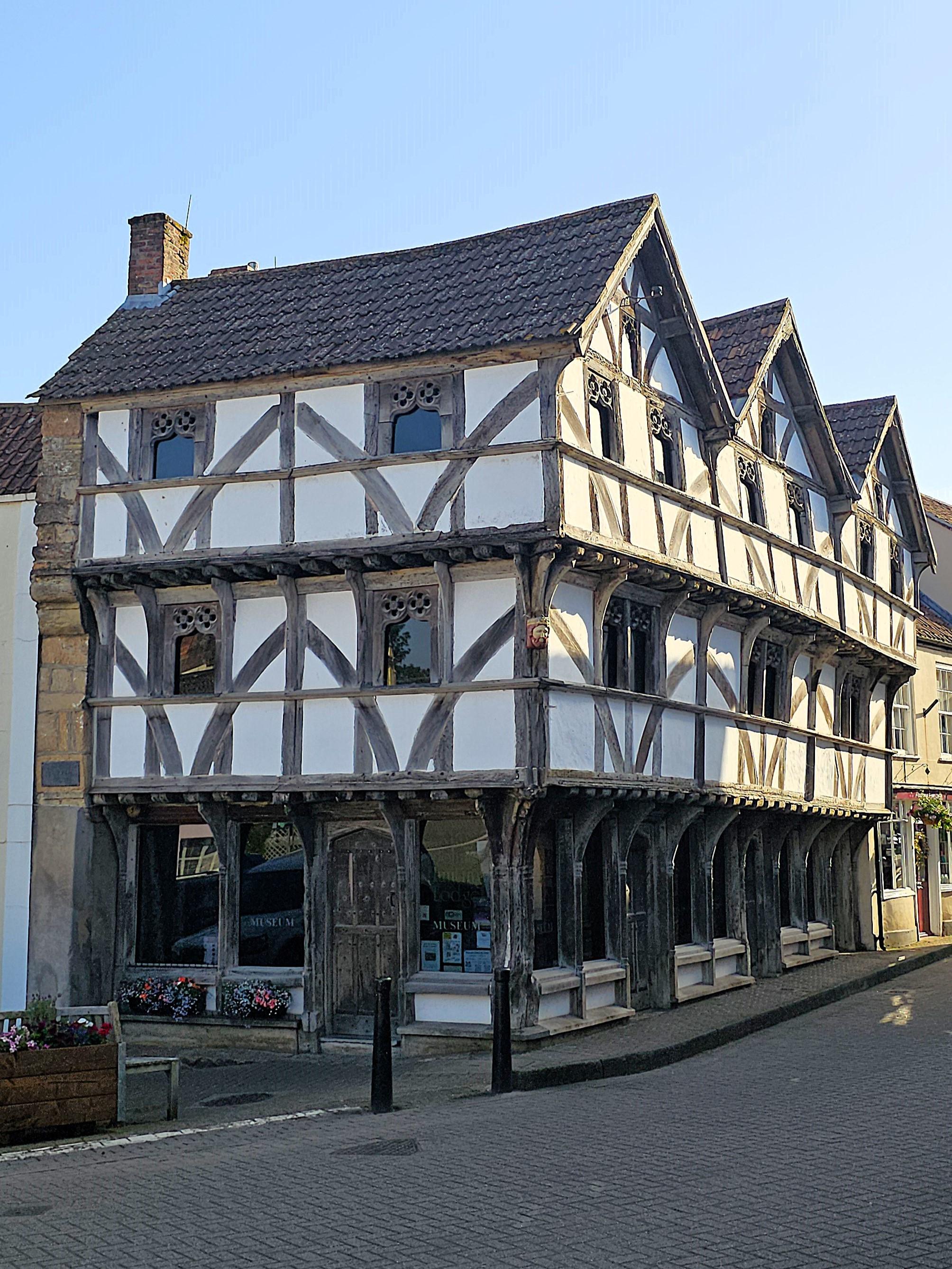 Half-timbered medieval house with three overhanging storeys and a triple pitched roof.