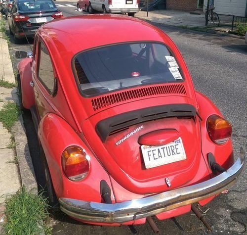 Red VW beetle with vanity license plate reading "FEATURE"