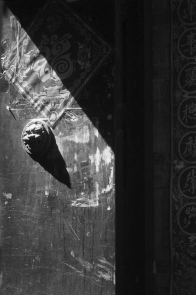 Ilford FP4 Plus 125 (FF)

English
A black-and-white photograph of a weathered wooden door with intricate carvings. The door features a faded, ornate design at the top, including a circular motif and what appears to be a small statue or sculpture of a figure. The surface of the door is textured, with visible cracks and scratches, and a large, dark, cone-shaped object is mounted on it. The image captures the door in partial shadow, highlighting its aged and rustic appearance.
中文
一张黑白照片，展示了一扇有精美雕刻…