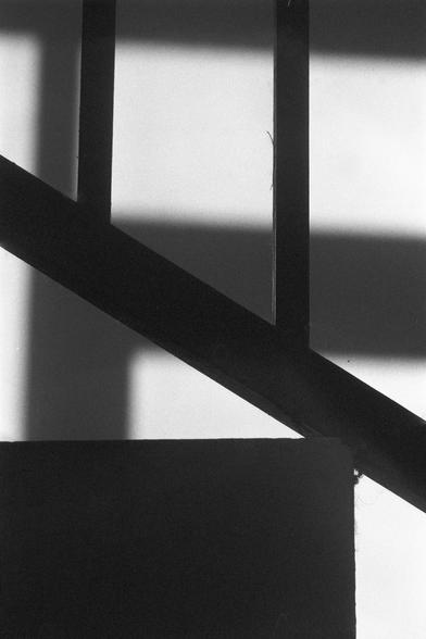 Ilford FP4 Plus 125 (FF)

English
A black-and-white photograph focusing on the shadow of a diagonal beam cast on a wall. The beam creates a sharp, angular shadow that intersects with the vertical and horizontal lines of the wall and frames, resulting in a stark contrast between light and dark areas. The image emphasizes the geometric interplay of light and architecture.
中文
一张黑白照片，聚焦于一根斜梁在墙上投下的影子。这根梁的影子形成一个锐利的角度，与墙面和框的垂直和水平线相交，制造出光线与阴影之间的强烈对比。照片强调了光线与建筑结构之间的几何交织。