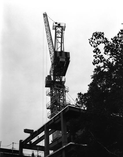 Lucky LUCKY SHD 400 (6x7)

English
A black-and-white photograph of a construction site featuring a tall tower crane. The crane's long arm extends upward, with its counterweights and cabin visible. The structure is surrounded by an incomplete building framework, with exposed concrete and steel beams. Trees are partially visible on the right side of the image.
中文
一张黑白照片，展示了一个建筑工地上的高大塔吊。塔吊的长臂向上延伸，可以看到配重和操作室。周围是未完工的建筑框架，露出混凝土和钢梁。图片右侧部分可见树木。