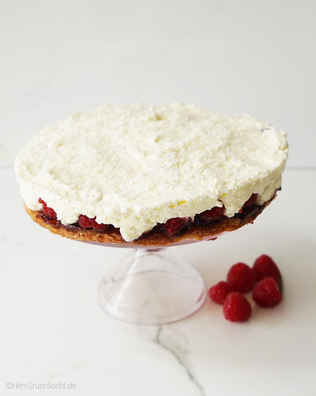 Himbeertorte mit Kokos auf einer rosafarbenen Etagere - alles auf weißem Untergrund