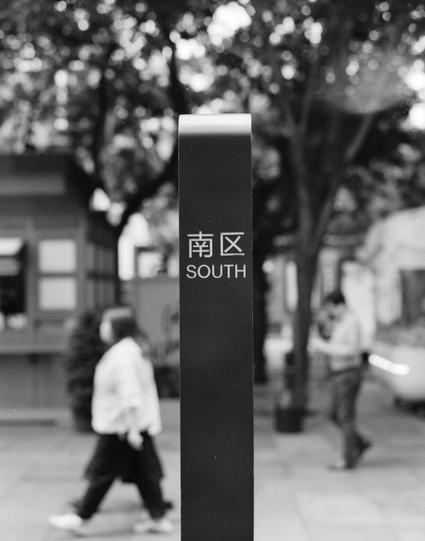 Lucky LUCKY SHD 400 (6x7)

English
A black-and-white image of a tall signpost with the text "南区" (Nanqu) and "SOUTH" written on it. The background is blurred, showing trees and people walking on a paved path.
中文
一个高大的标志杆，上面写着“南区”和“SOUTH”的黑白图像。背景模糊，显示树木和人们在铺设的小路上行走。