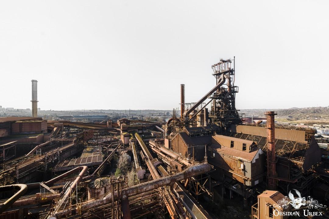 An aerial view of the vast, decaying Cockerill-Sambre Ougree Ironworks in Belgium. Rusting structures and towering machinery fill the scene