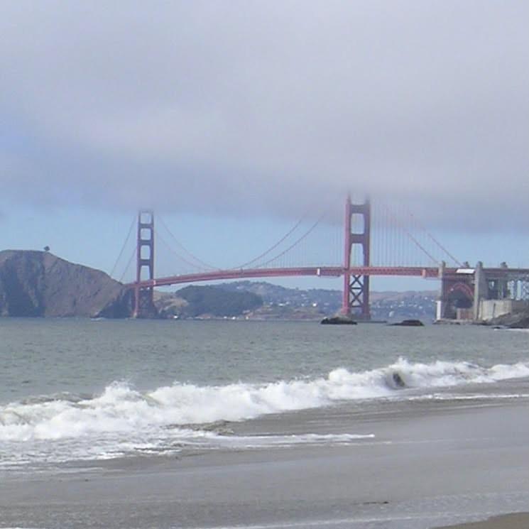 The Golden Gate Bridge in San Francisco on a grey-ish day. The tops of the bridge towers are shrouded in clouds.