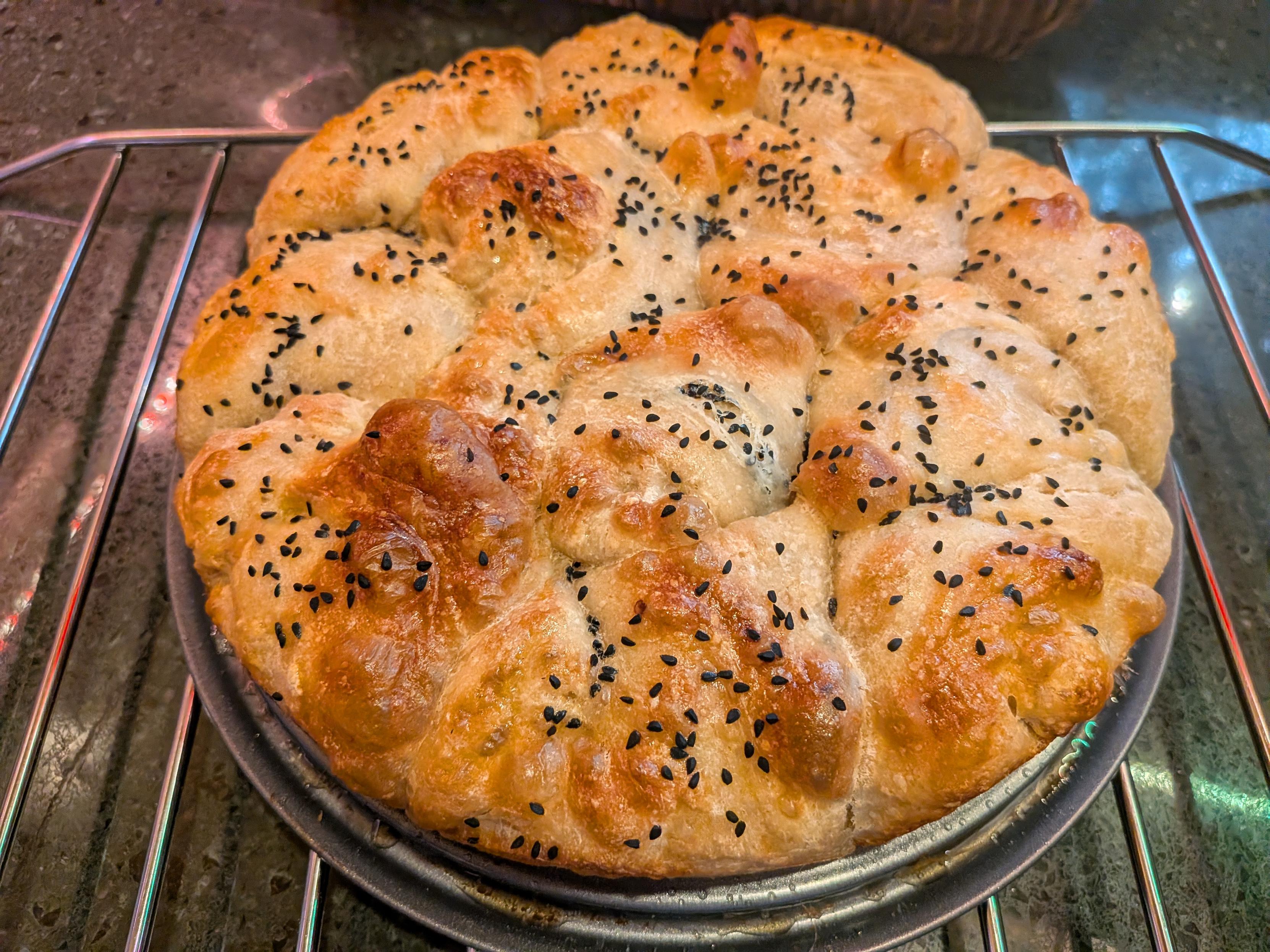 A round loaf of bread topped with nigella seeds