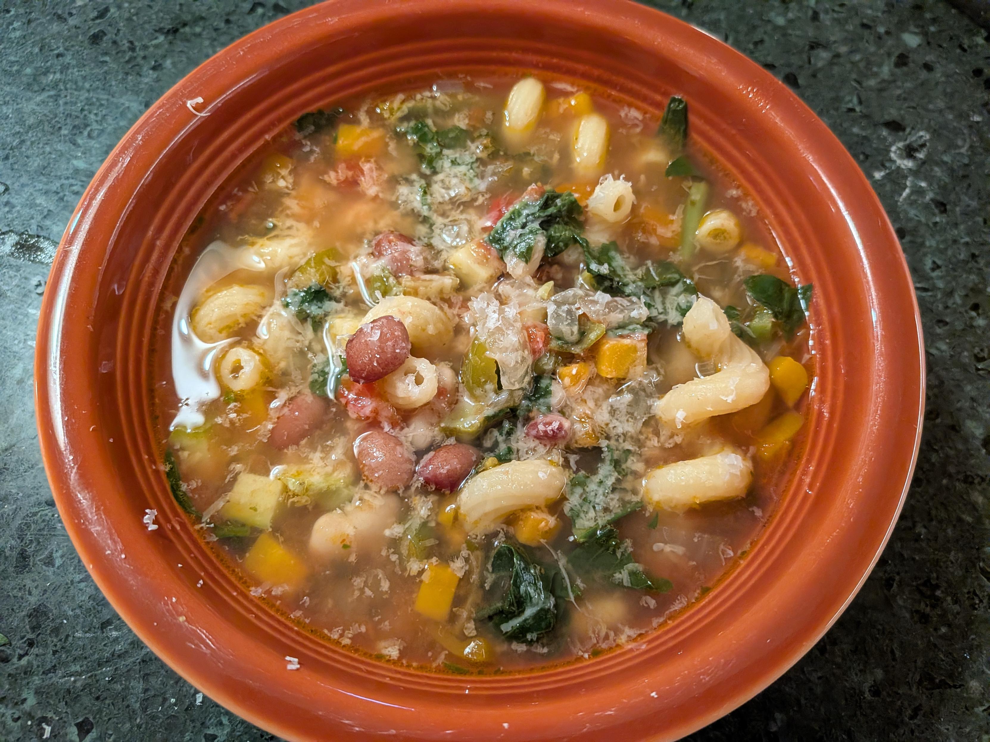 A bowl of soup with vegetables, beans, and noodles