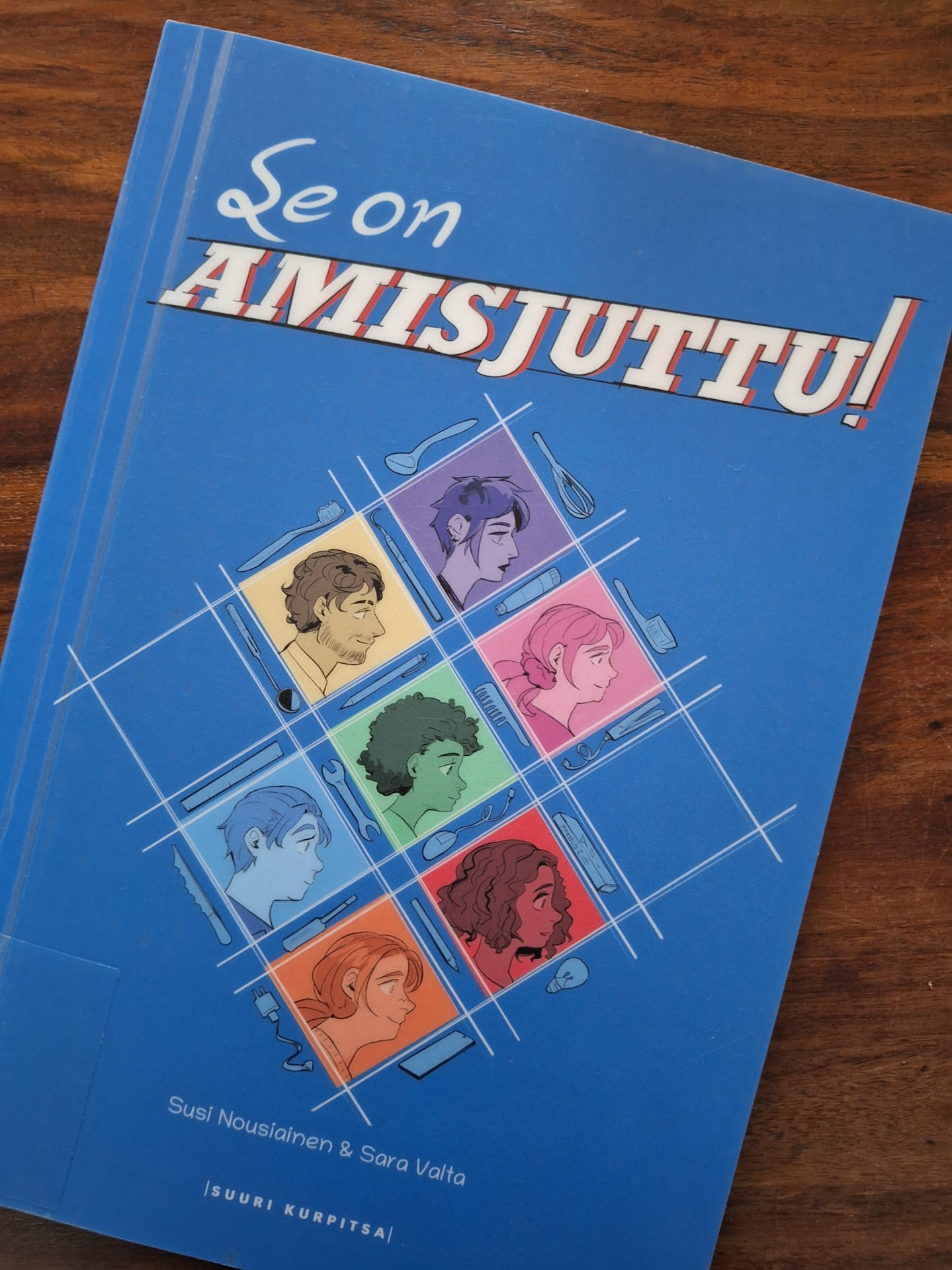 Sininen kansi, jossa ristikon sisällä tarinoiden amislaisten sivuprofiileja.