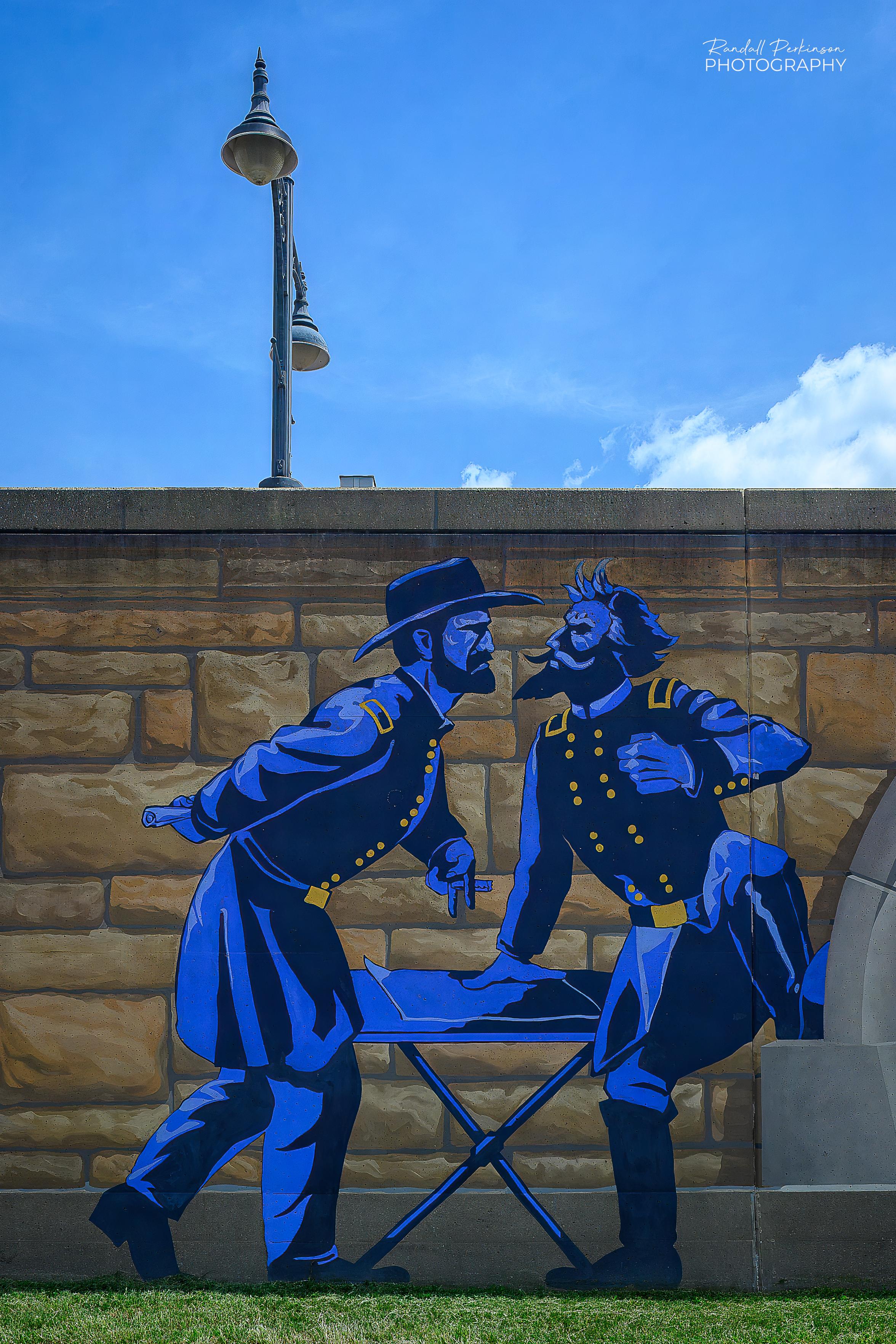A mural on a flood wall show two civil war soldiers arguing with each other.