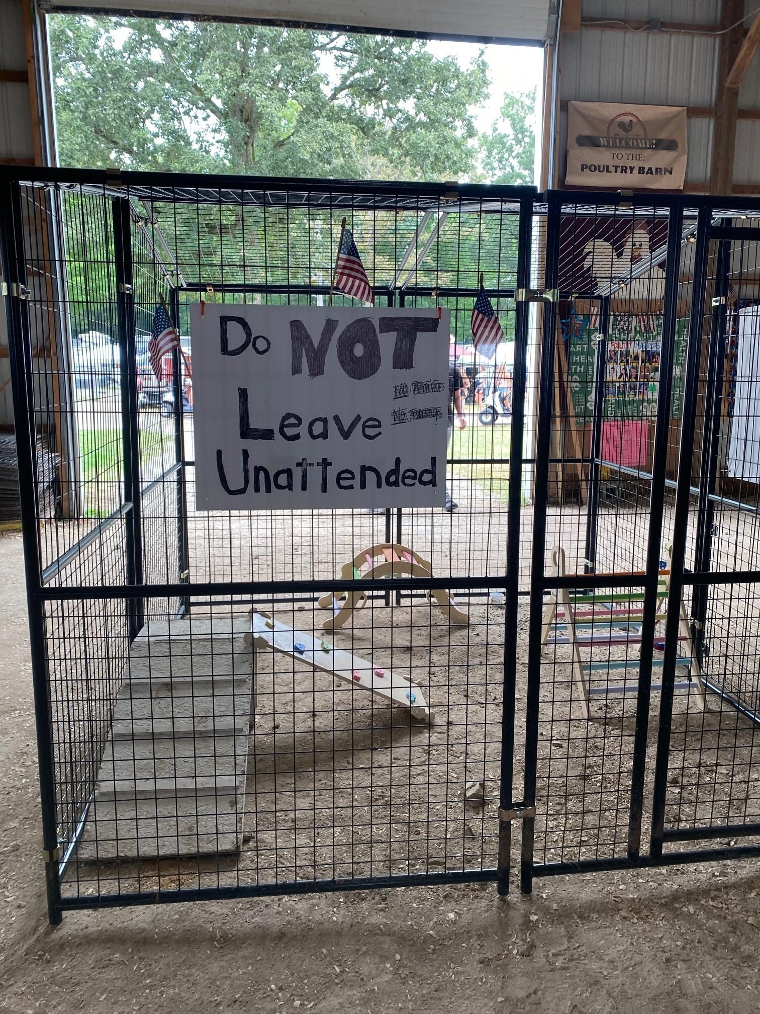 Color image of a children's play space inside a county fair building in Medina County, Ohio, USA. Image shows an empty play space set up for small children with toys inside, but no tots, and with a sign on the outside reading "Do NOT Leave Unattended."