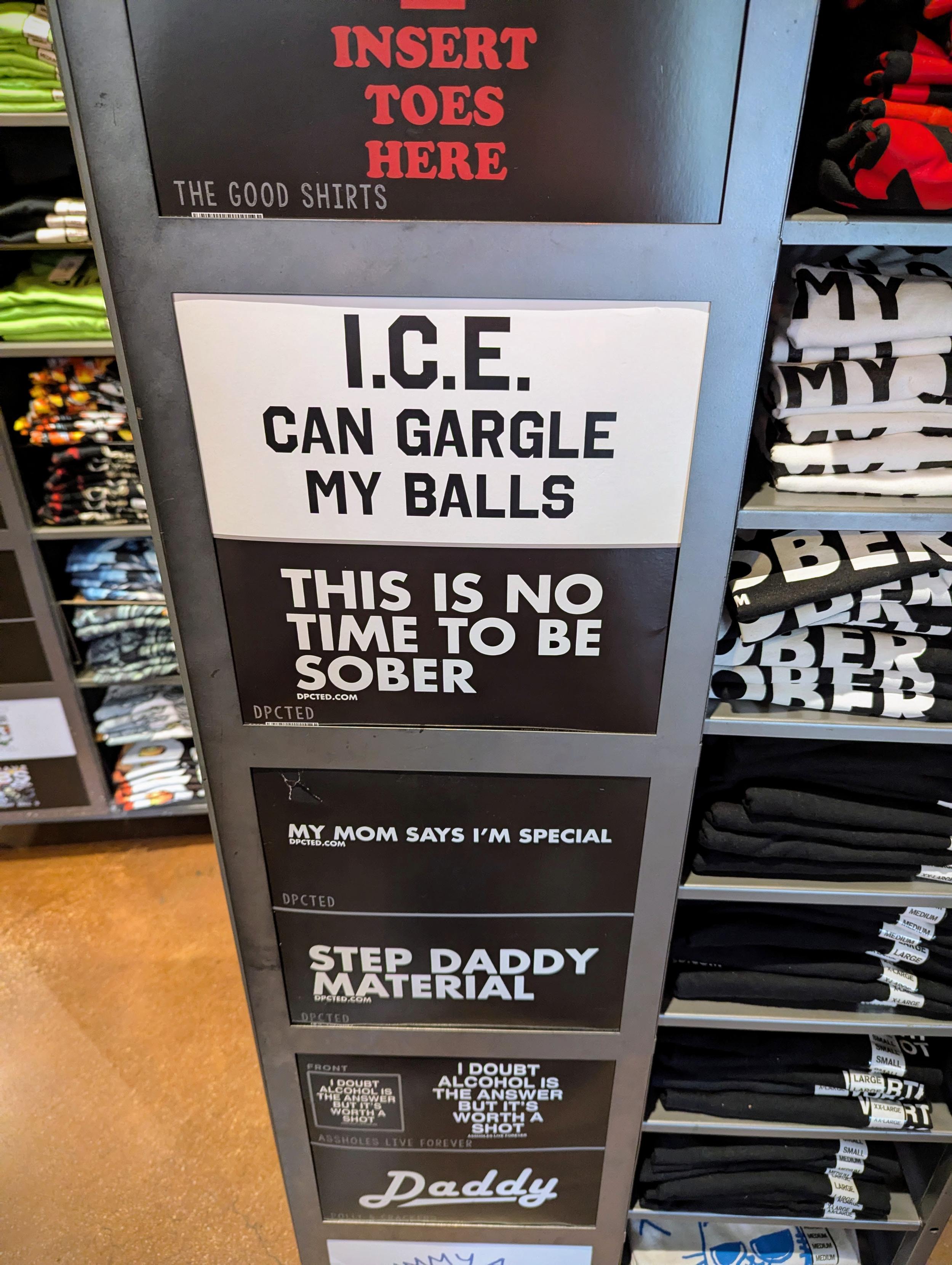 T-shirt display at Spenser's Gifts featuring one saying "I.C.E. Can Gargle My Balls."