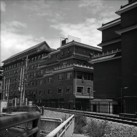 Lucky LUCKY SHD 100 (6x6)

English
A black and white photograph of a group of buildings adjacent to a seemingly abandoned railway, as it is accessible to pedestrian paths. The buildings are in a traditional Chinese rooftops but with modern touches. The sky is cloudy but bright. And one can see some power lines on the far left of the image.

中文
一張黑白照片.照片中有幾棟靠近鐵軌的樓房.鐵軌看似廢棄,因為似乎可以直通人行道.樓房的屋頂看似傳統中式建築,但又有摩登的韻味.天空明亮但多雲.照片左側可以看到一些電線穿過.