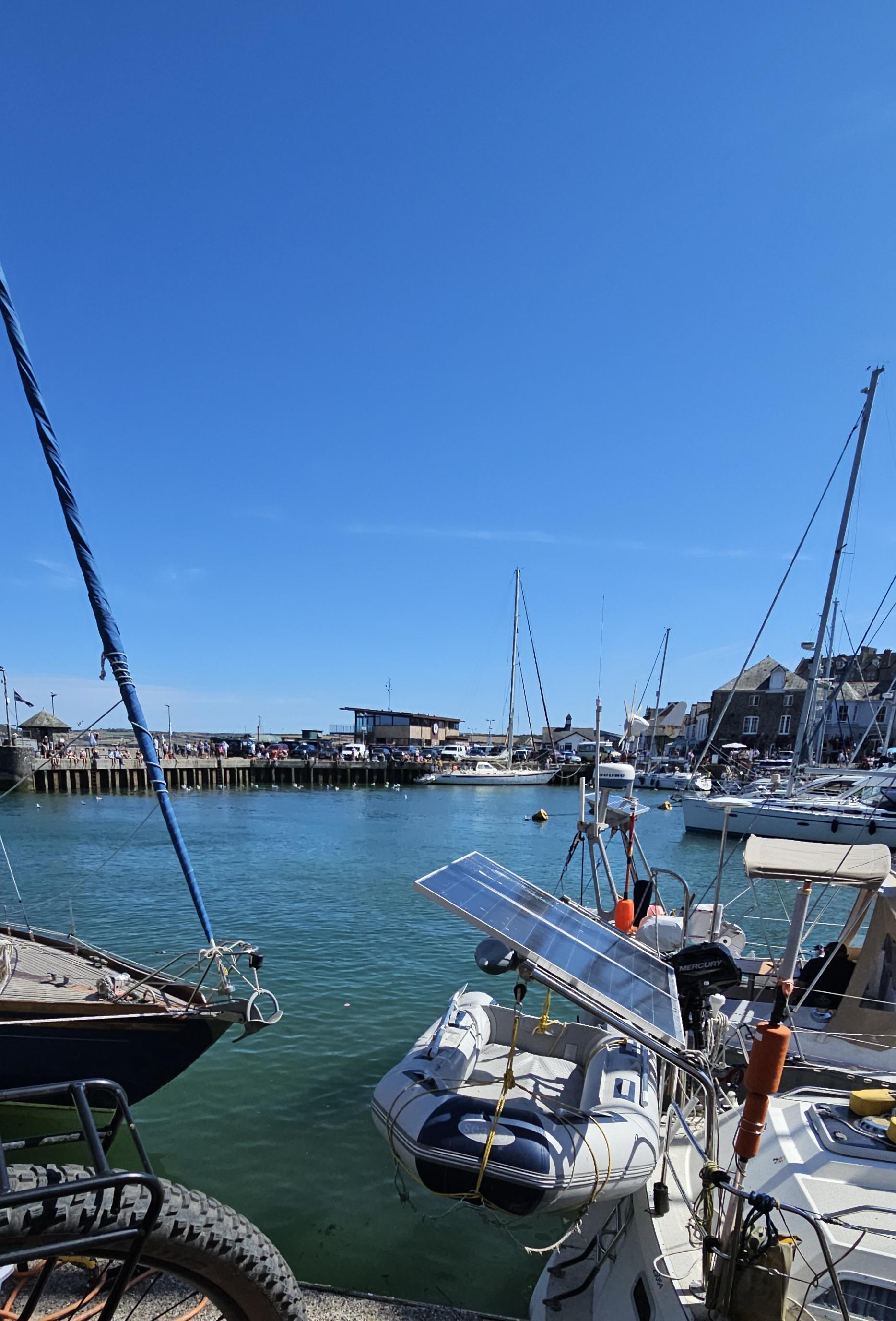 View across a busy, blue harbour, crowded with small boats.