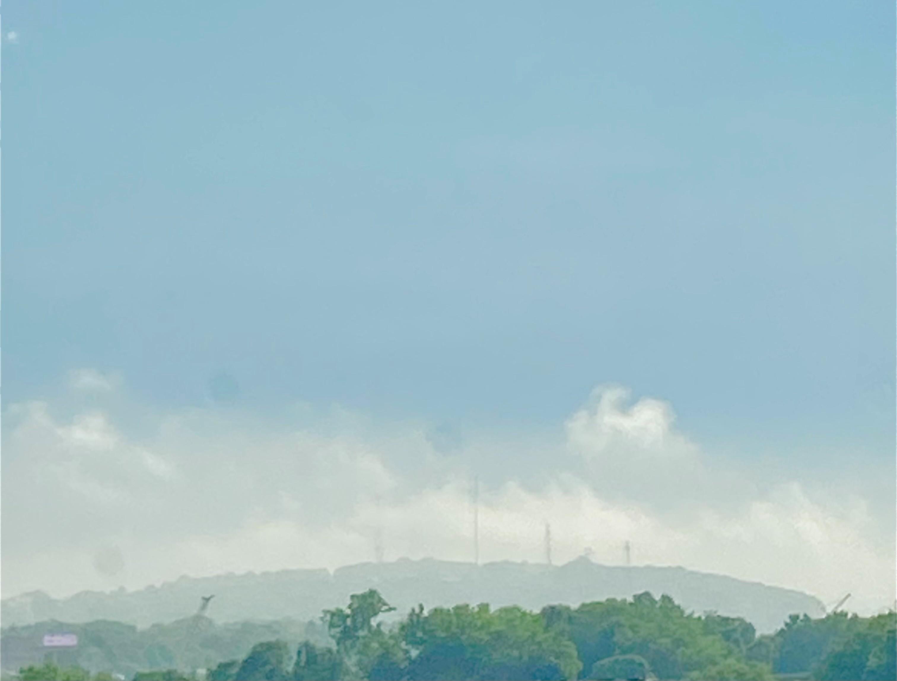 Color image of cumulus clouds pausing above Chapel Hill in Akron, Summit County, Ohio, USA 11 August 2026. Image shows white and gray cumulus clouds parked above Chapel Hill, a moment of sun parsed away by darker clouds coming, over a landscape of trees in full summer leaf.