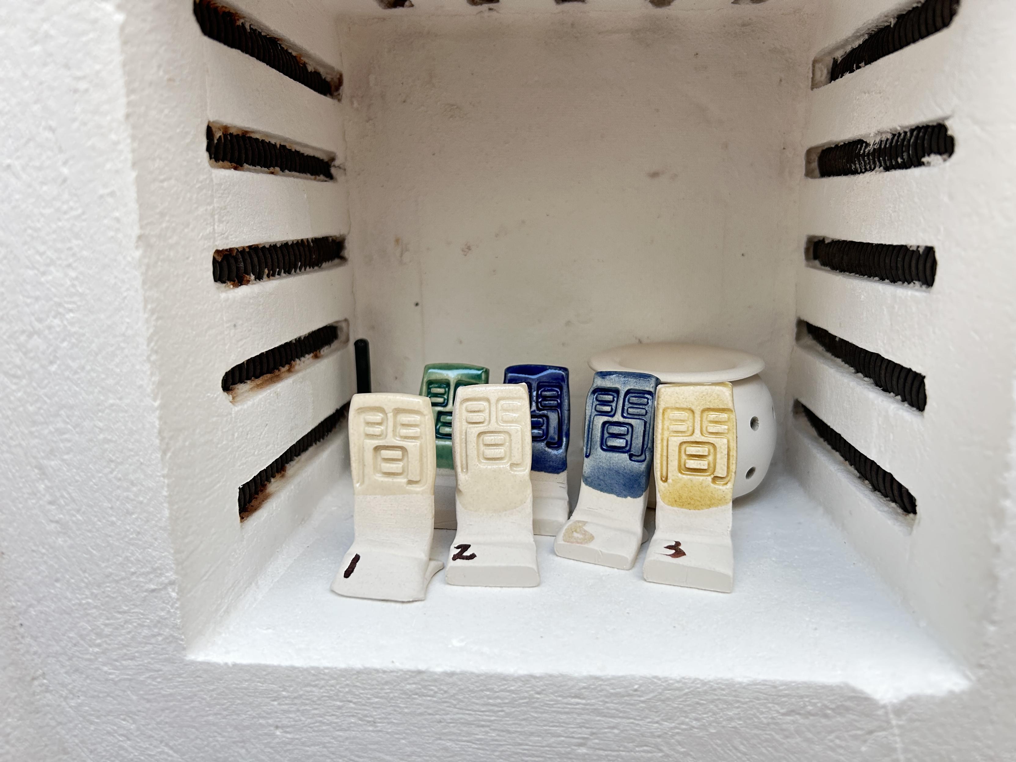 Little standing test tiles of different colours in a tiny kiln