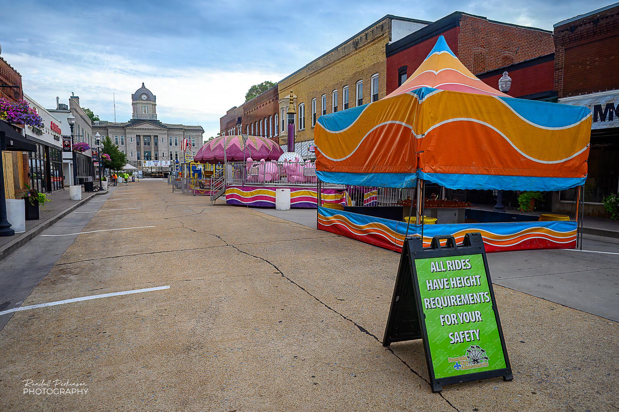 A quiet, early Friday morning on the streets of Jackson, Missouri prior to the opening of a weekend downtown carnival.  Booths and rides can be see set up in the street leading up to the Cape Girardeau County Courthouse.