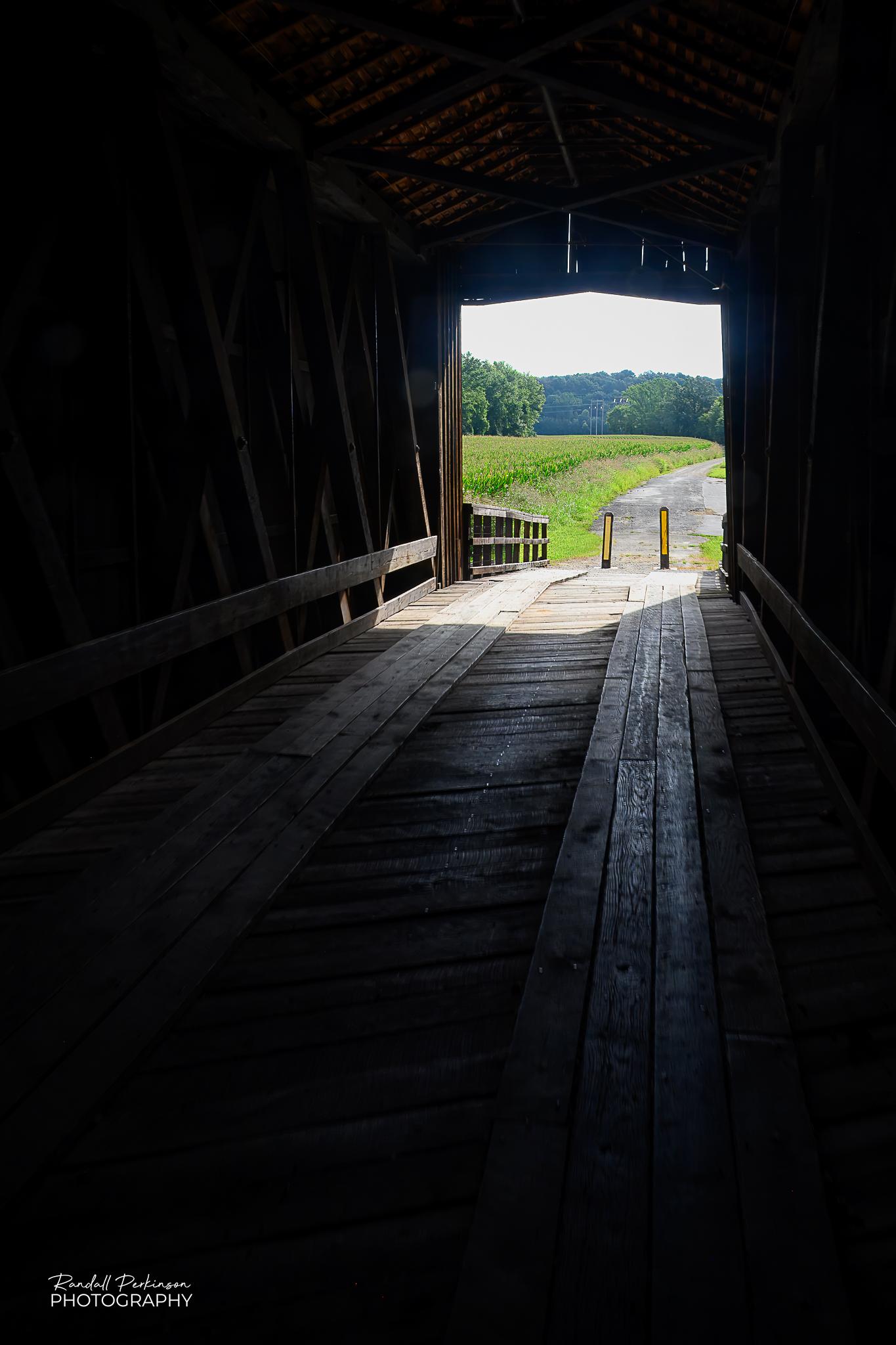 Looking out the end of a covered bridge from inside of it.