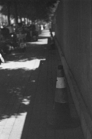 Ilford HP5 Plus 400 (FF)

English
A black and white photograph of a traffic cone standing on a sidewalk, in the shadows of a wall. Different bicycles and motorcycles are vaguely visible in the background.

中文
一张黑白照片。照片中一个交通锥在行人道边石墙的阴影里。背景中有相当数量的自行车和摩托车。