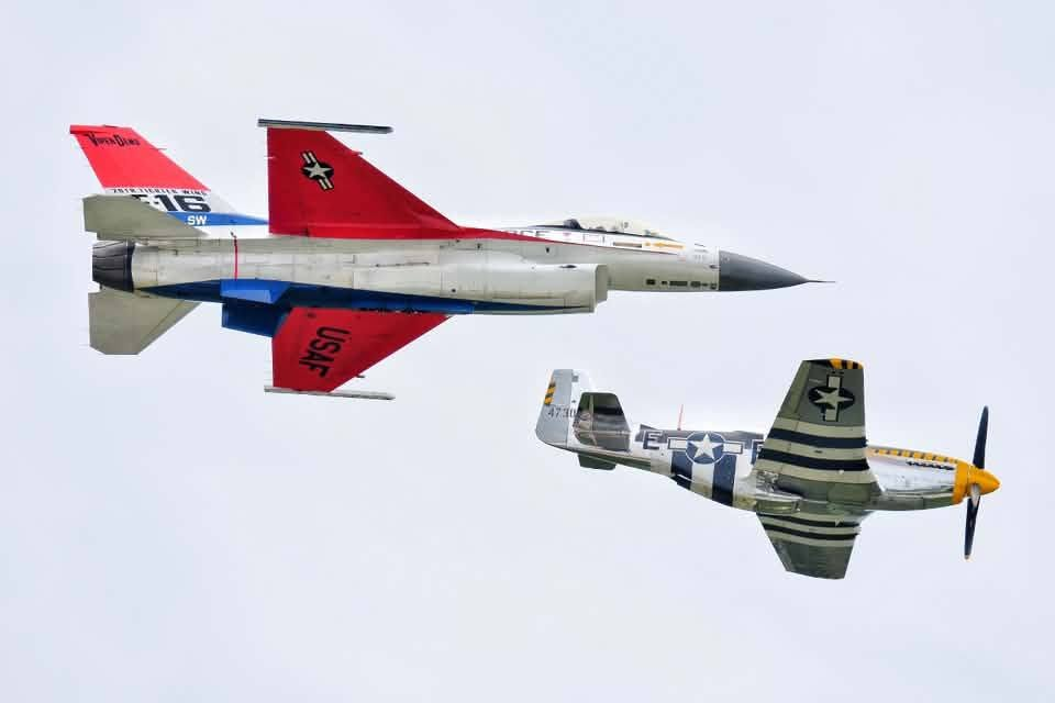 Color image of a P51 Mustang and an F16 Viper during the Heritage Flight, Props and Pistons Festival, Akron, Summit County, Ohio, USA, 15 August 2026. Image shows a USAF F16 Viper flying in close formation with a WWII P51 Mustang in the cloudy skies over the Akron-Fulton International Airport - the Akron Municipal Airport during the festival.