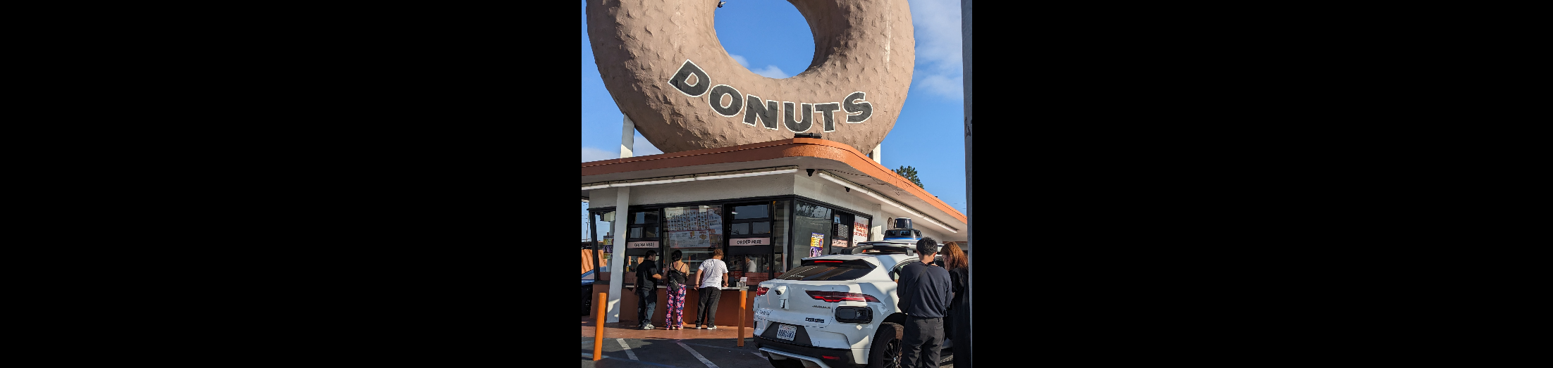 Waymo discharging passengers under Randy's giant doughnut