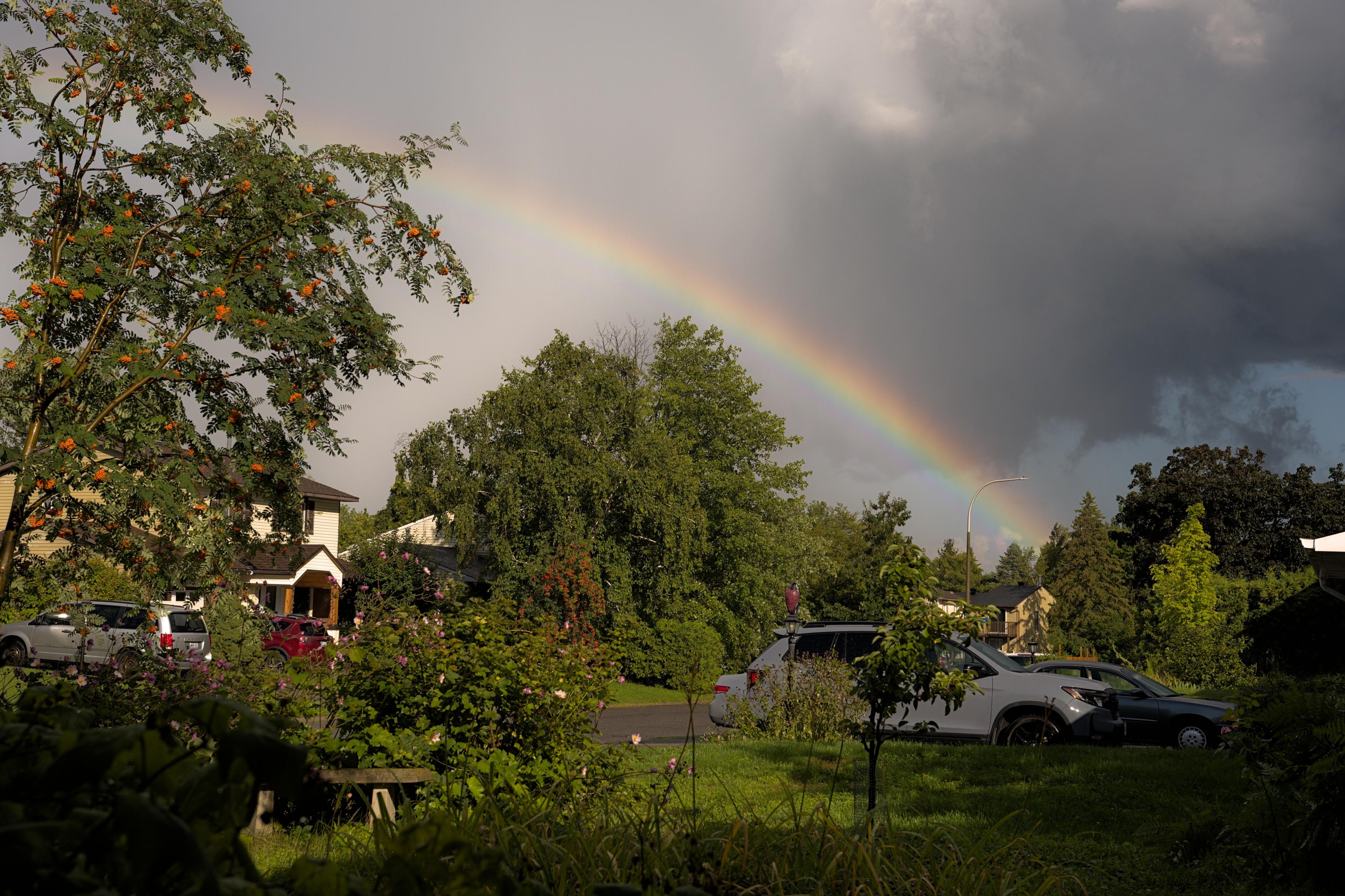Happy under the rainbow, storm clouds above.