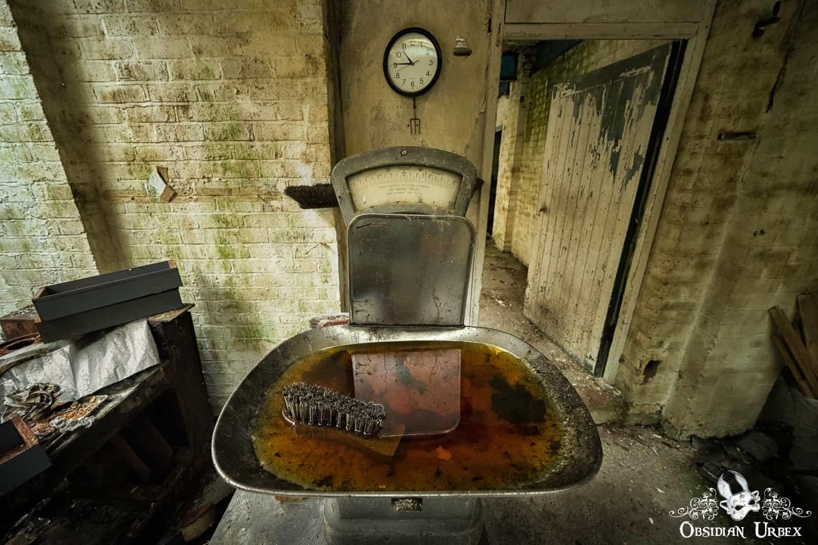 old metal weighing scales, filled with rusty water and an old brush head
