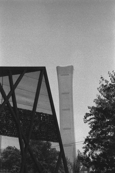 Ilford HP5 Plus 400 (FF)

English
A black and white photograph of the skyline of a city. A skyscraper stands to the right of a geometric metal structure. To the right of the picture stands a tall tree, partially visible. The sky is bright and gradient.

中文
一張城市天際線的黑白照片.一棟摩天大樓在一個金屬幾何形的建築的右側. 照片的右側有一顆高大的樹木,部分可見. 天空明亮層次分明.