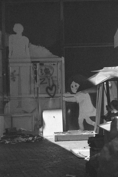 Ilford HP5 Plus 400 (FF)

English
A black and white photograph of murals and doodles on a wall. It features a young girl pushing some crates, which are part of a frame that is on the wall. Some calligraphies are on the wall, vaguely seen.

中文
一幅牆體塗鴉的黑白照片.塗鴉中一個小女孩似乎在推什麼東西,類似一些木箱.木箱是牆體上某些邊框 本來的一部分.塗鴉中有一些文字隱約可見.
