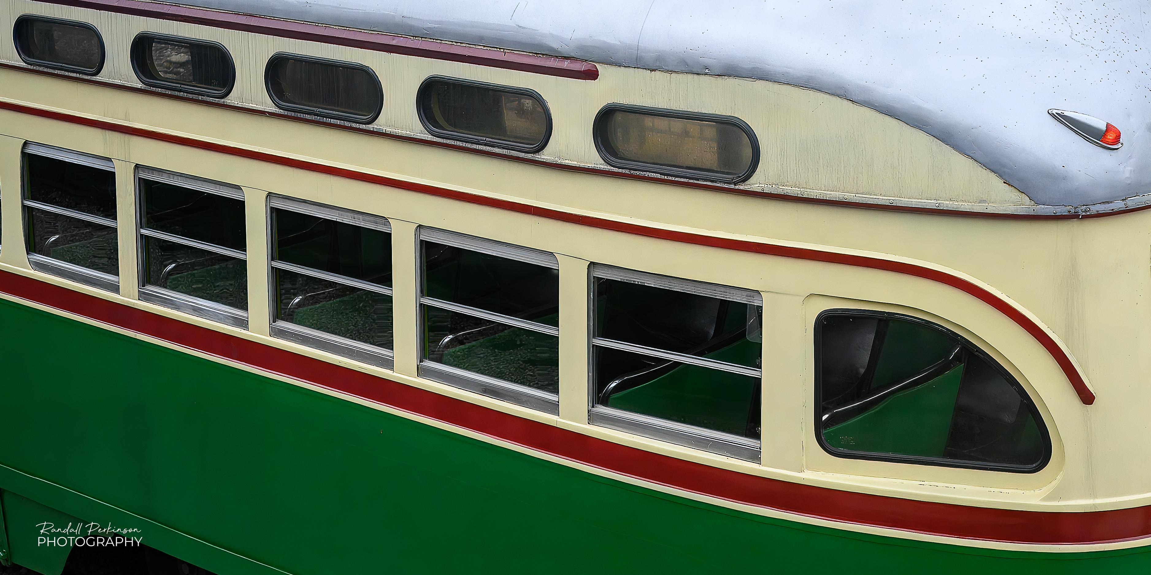 A photo of the back 2/3 of a President's Conference Committee streetcar built in 1947 by the St. Louis Car Company for SEPTA.  It features the authentic, eye-catching Philadelphia "wings" livery featuring green and cream colors with bright red accents.  It is currently operation within the confines of the National Museum of Transportation in Kirkwood, Missouri.