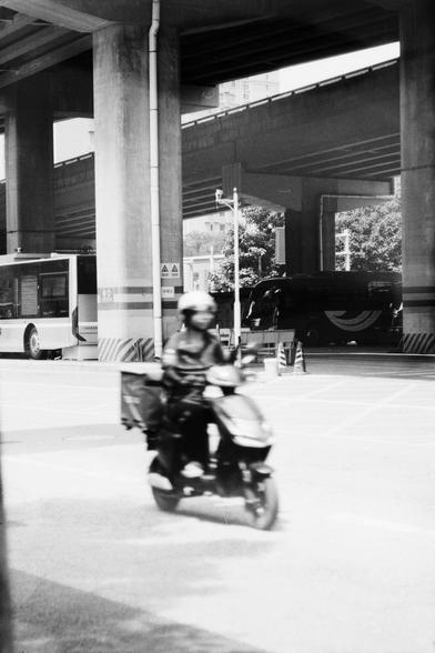 ERA 100 (FF)

English
A black and white photograph of street scene. A blurry person riding a motorcycle can be seen in the foreground. A bus is going under the flyover in the background.

中文
一张街景的黑白照片.前景中可以看到一个模糊的骑着电瓶车的人.后景中一辆公车从高架桥下经过.