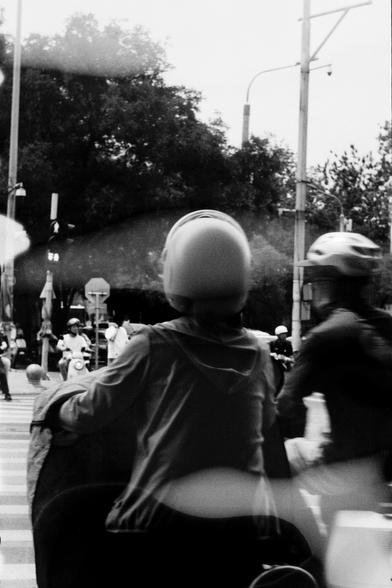 ERA 100 (FF)

English
A black and white photograph of street scene at a crossroads. The foreground is two motorcyclists with helmets. The background has more people trying to cross the road.

中文
一张黑白照片的十字路口街景.前景中有戴着头盔骑电瓶车的两人.背景中可以看到更多人过街.