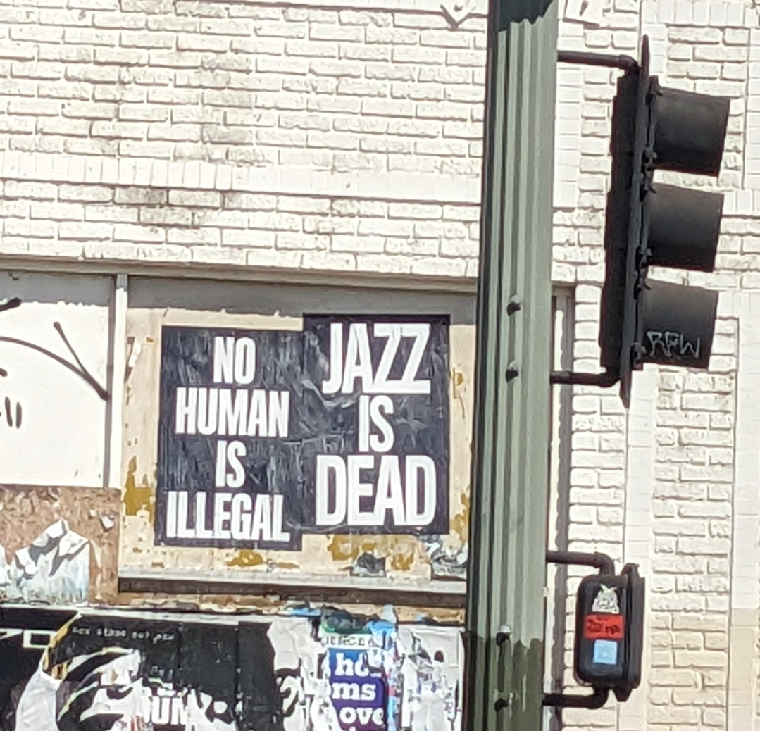 Signs say Jazz is Dead and No Human is Illegal