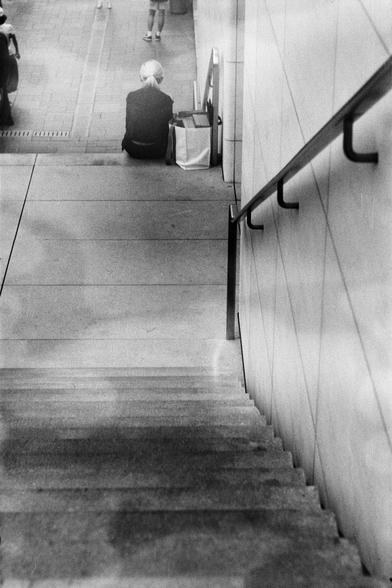 ERA 100 (FF)

English
A black and white photograph a street scene. A person can be seen sitting on the bottom of a staircase, which is on the side of a wall with handrails attached to it.

中文
一张街景的黑白照片.一个人坐在楼梯的下方.旁边装着把手的墙壁清晰可见.