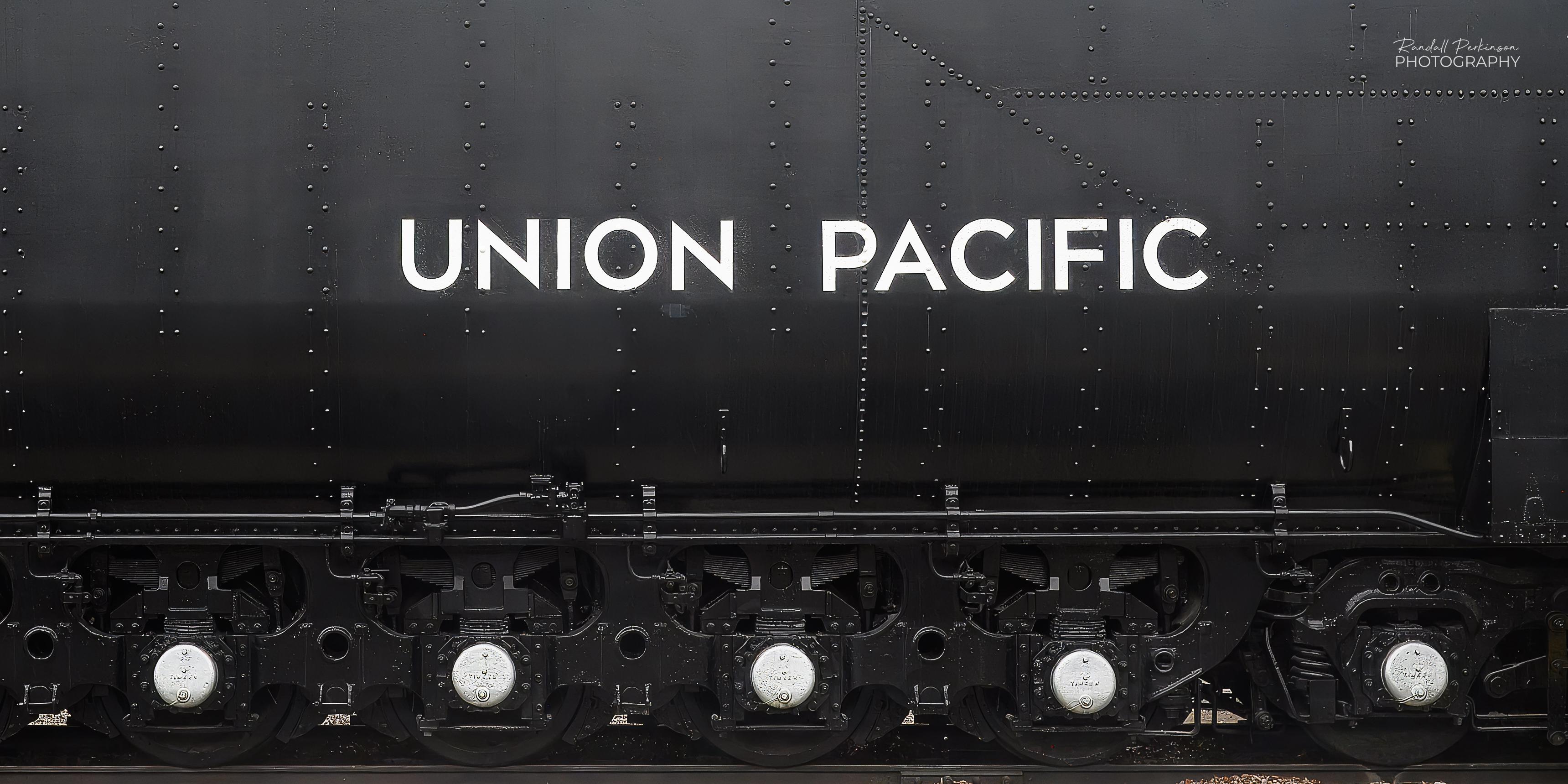 The side of the tender portion of Union Pacific Big Boy 4006 at the National Museum of Transportation in Kirkwood, Missouri.  5 axles are evenly spaced under the length of the tender in the picture.