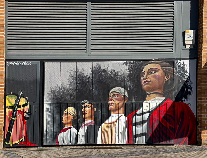 Un mural en una puerta metálica, están dibujados las figuras de cuatro gigantes de un comparsa.