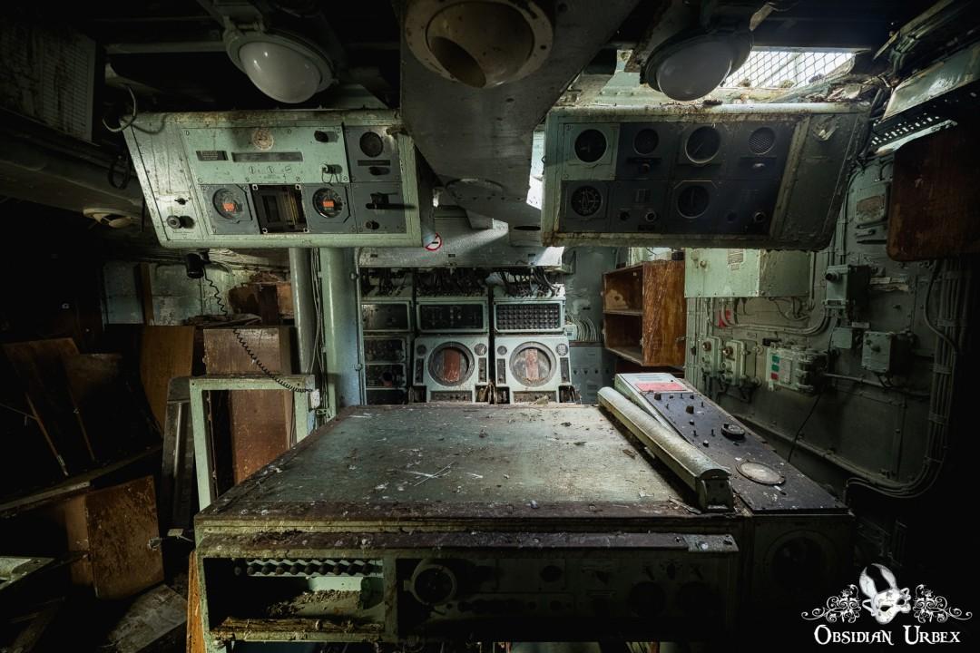 Radar room with monitors and table, two consoles with dials above the table