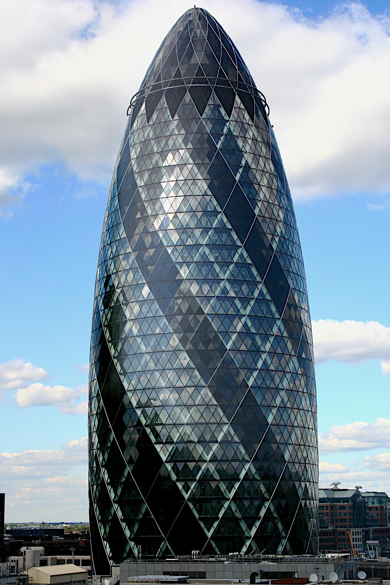 Less than two years after its December 2003 completion, 30 St Mary Axe, previously the Swiss Re Building and widely known as The Gherkin for its shape. Entirely glass clad the 40 storey building widens slightly from the ground level foot print and then narrows creating a curve to the apex. There the building is seen against a bright sky with clouds, a distant horizon low on the left and a mid rise building in the middle distance to the right.  A view that is no longer possible because of subsequent building.

Canon EOS 350D DIGITAL
ISO: 200
Shutter Speed: 1/200
Aperture: 10.0

Lens: 18.0 - 55.0 mm
Focal Length: 38.0 mm (35 mm equivalent: 61.6 mm)
Hyperfocal Distance: 7.80 m
Field Of View: 32.6 deg

GPS Position: 51° 30′ 52″ N, 00° 04′ 49″ W

2005:09:17 14:42:52
Copyright: © Matthew Malthouse 2005