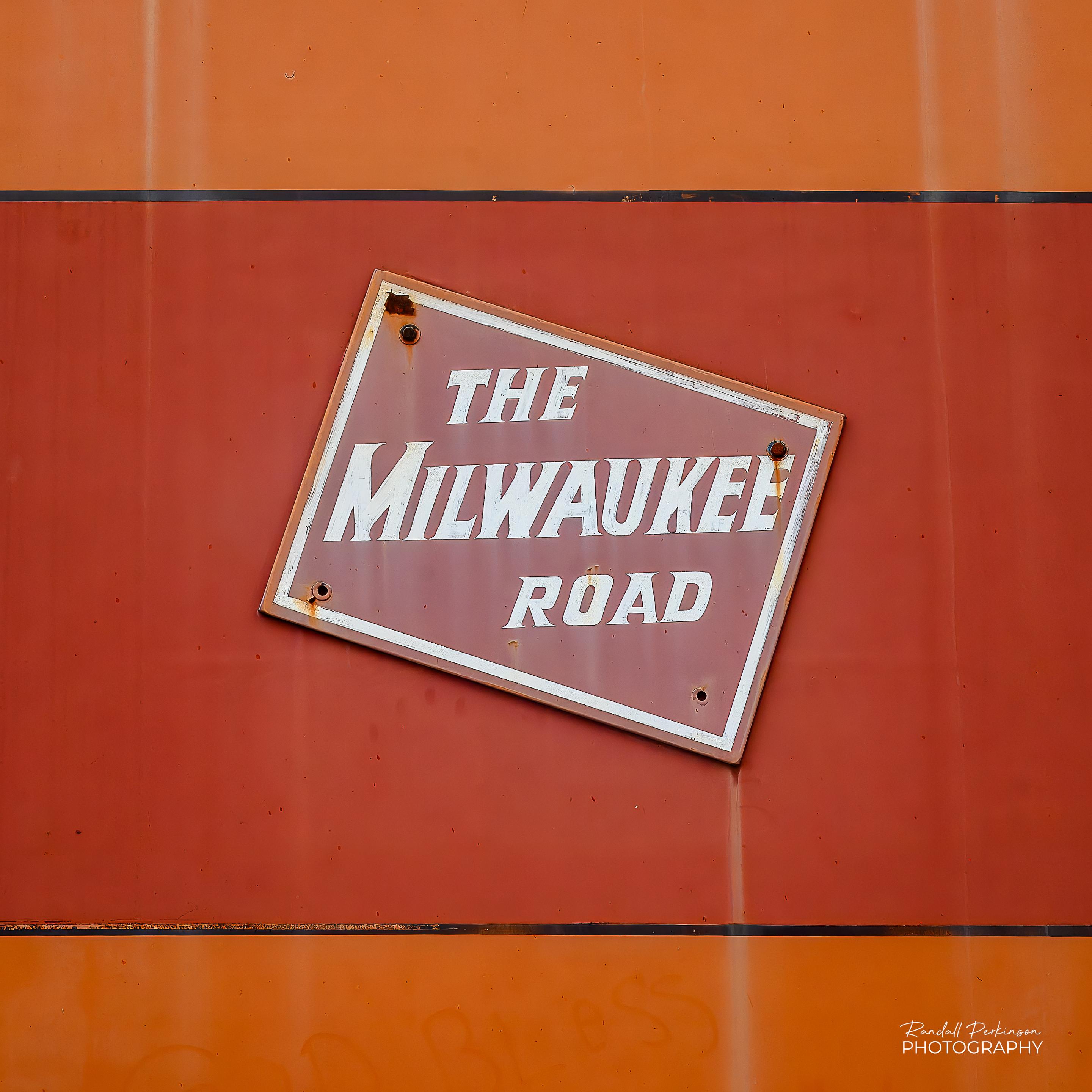 The logo of "The Milwaukee Road" railroad on the side of a locomotive or train car.