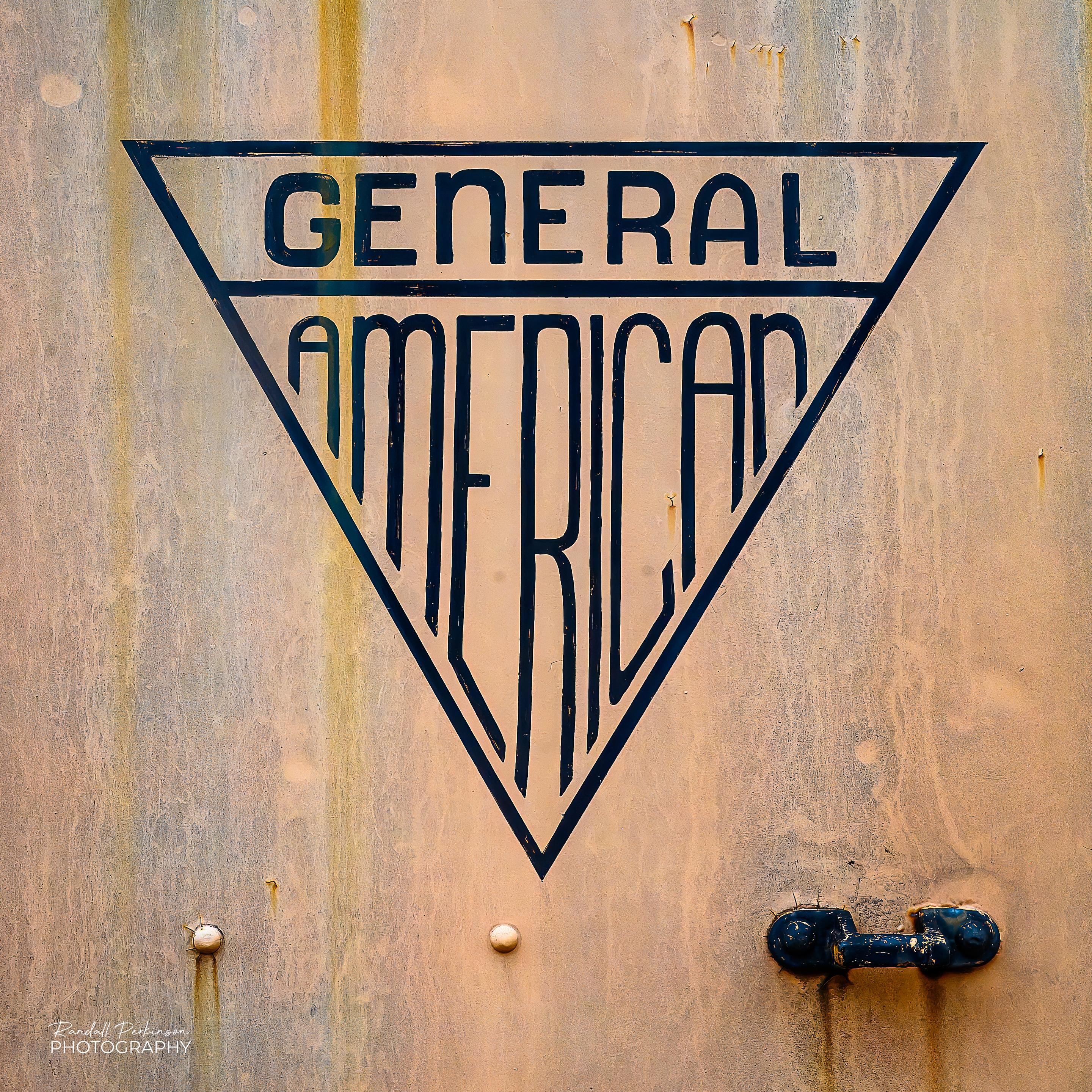 The triangular logo of General American on the side of a locomotive or train car.
