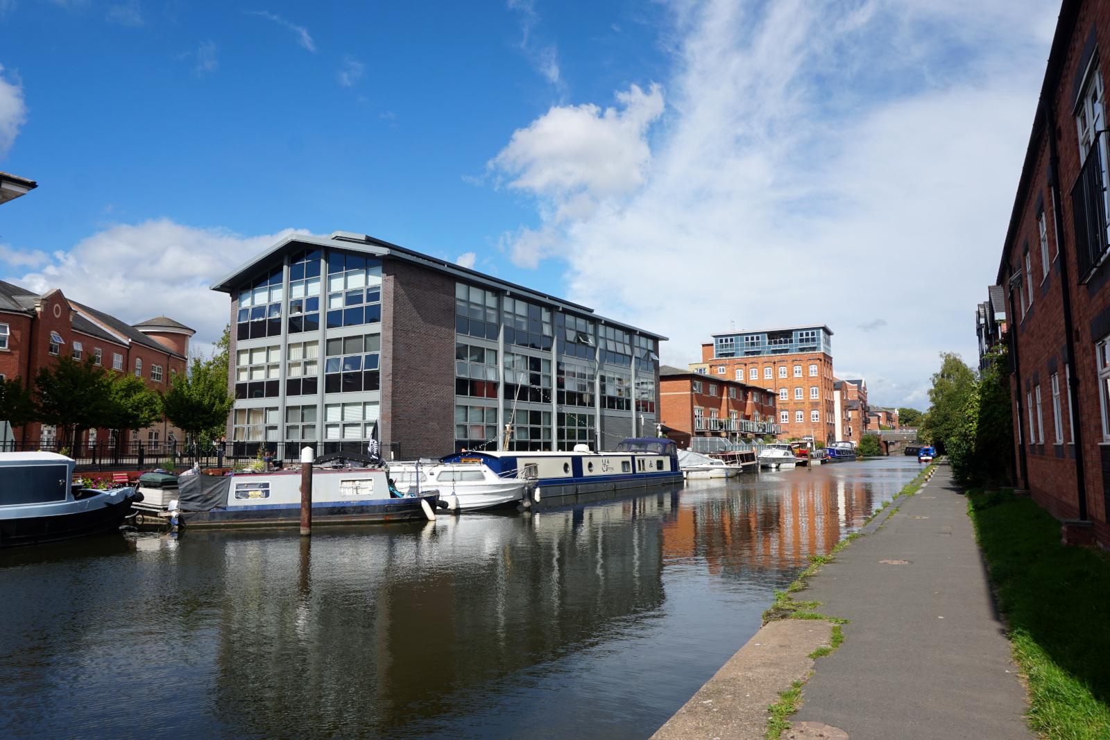 A view up the canal towards Worcester city, several canal boats moored on the far side in front of office buildings