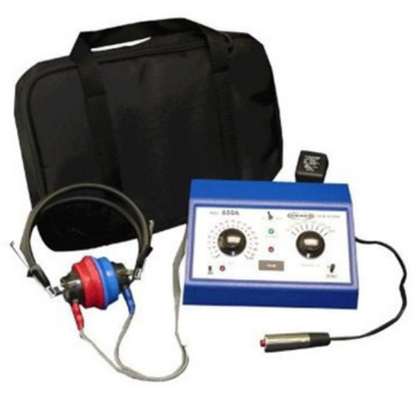 Color image of audio/hearing test equipment. Image shows a black satchel, headphones with labeled sides in red and blue, and an instrument designed to measure hearing responses.