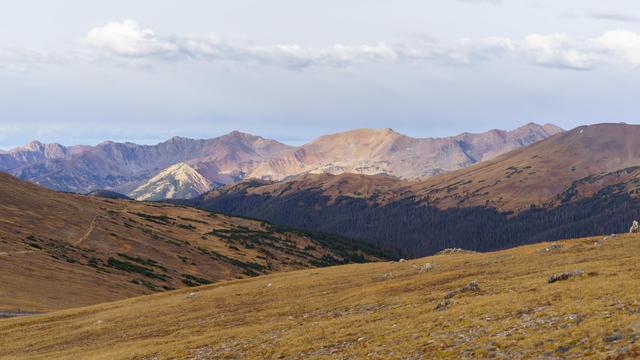 Photo from Rocky Mountain National Park looking southwest from Trail Ridge Road toward the Never Summer Range across a couple of valleys. At the left a portion of the Ute Trail is visible, heading from the Trail Ridge Visitor Center down, eventually, to the Kawaneechee Valley. The trail was one of several used by the indigenous Ute people and others to cross what are now called the Rocky Mountains to come out to the eastern plains. October 2015.