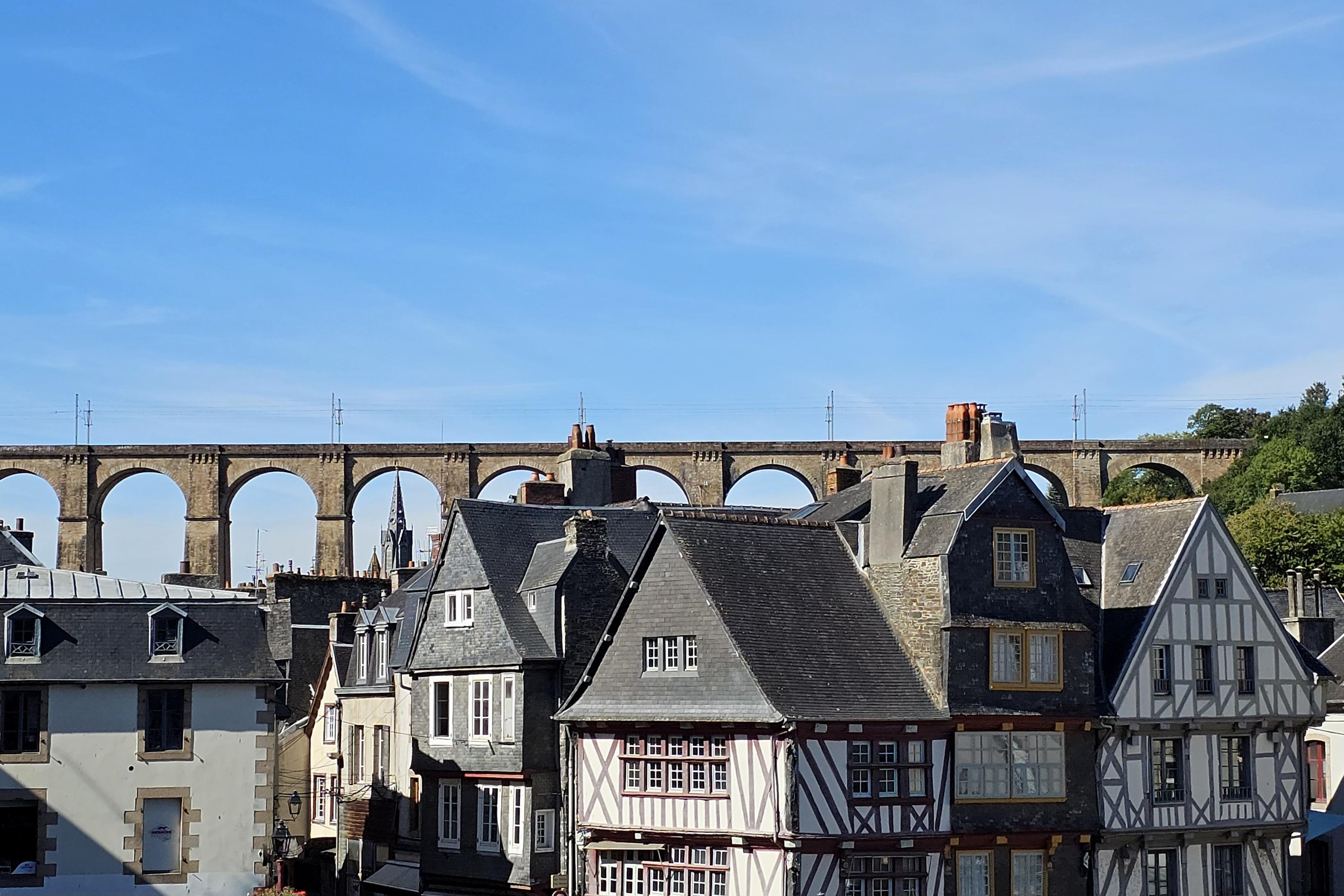 View of half-timbered houses, with an imposing railway viaduct in the background.
