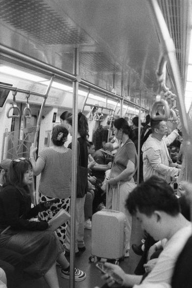 Ilford Delta 3200 (FF)

English
A black and white photograph of the interior of an underground train. Passengers can be seen standing or sitting. Some of them looking at their phones, some holding onto their luggage.

中文
一张地铁内部的黑白照片.照片中有很多乘客,或站或坐.有的在看着手机,有的扶着行李.