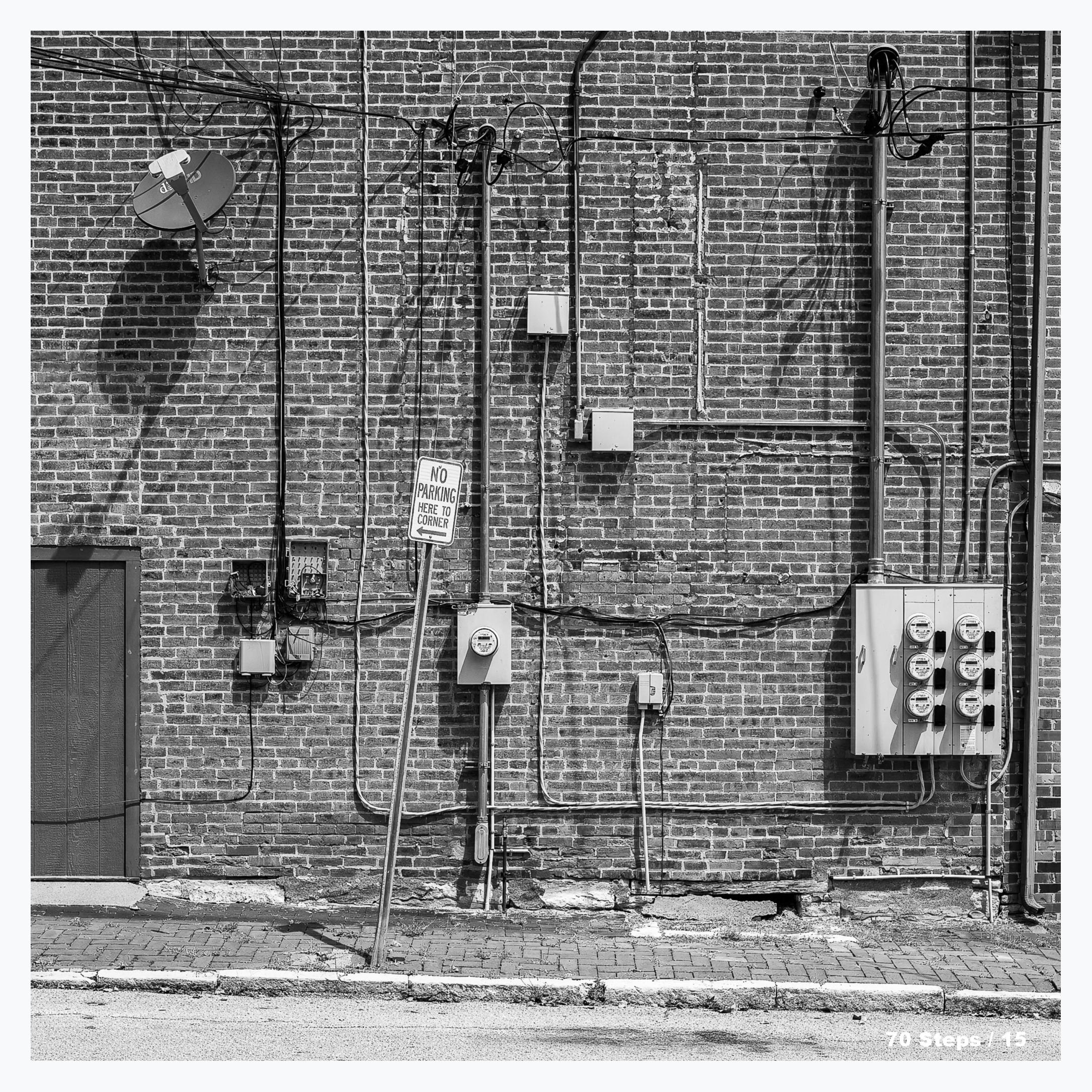 Various electrical and communication wiring and meters on the side of a brick building.